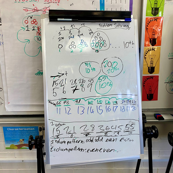 A whiteboard in a classroom full of numbers for a mathematics lesson.