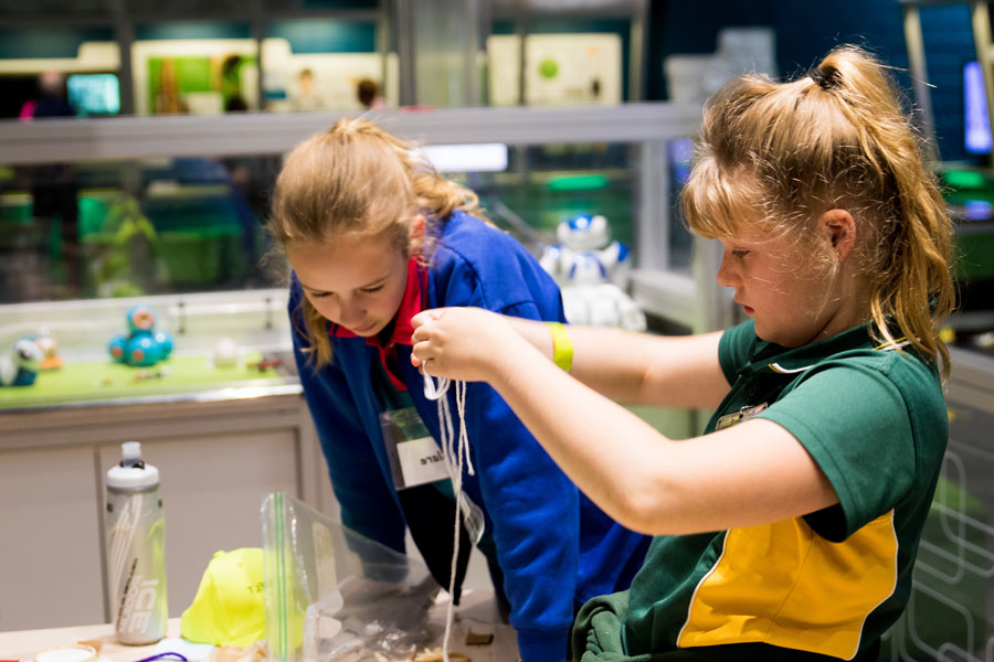 Two young girls playing holding up string in a lab.