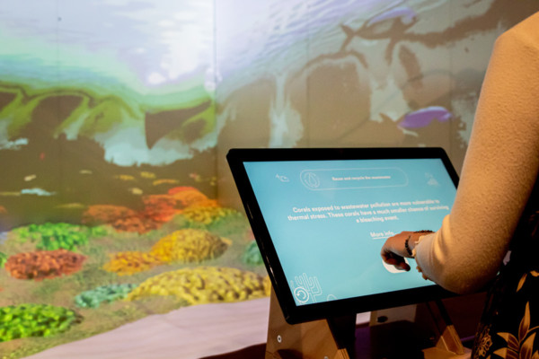 Interacting with a screen with 3D projection of a coral reef in the background