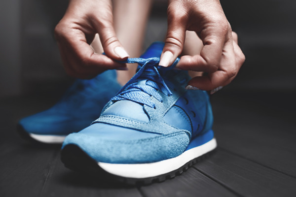 Woman ties up shoelaces on sneakers. Close up view.