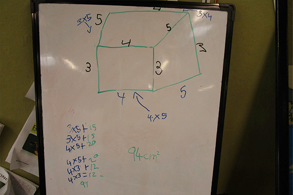 A 3d rectangular shape with dimensions annotated on a whiteboard.