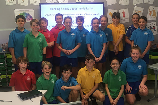 A classroom of year 6 primary students smiling for a group photo.