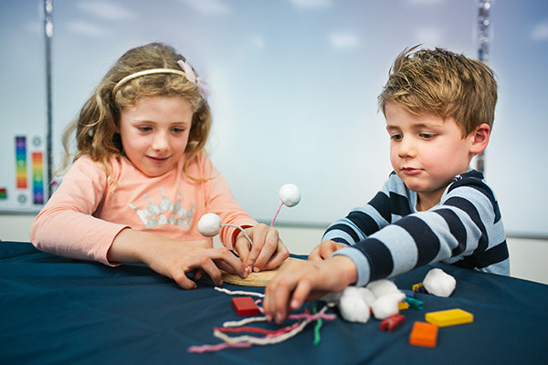 Two young children under 6 playing in the Tinkering Space with cardboard and craft items.