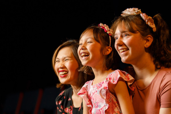 A mother and her two children laughing and smiling enthusiastically together.