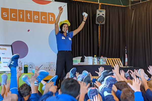 Science presenter excitingly presenting a show in front of primary students
