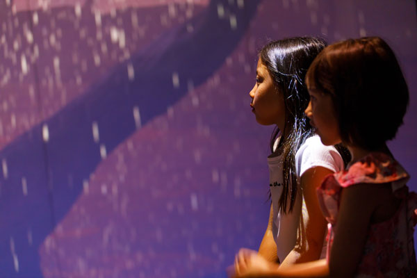 Two girls immersed in light projections exhibition