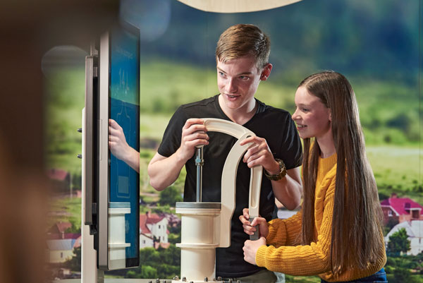 Teenagers learning about water consumption through a hands-on exhibit