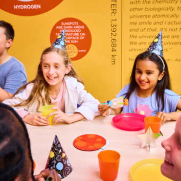 Three smiling children sitting at a table for a birthday party