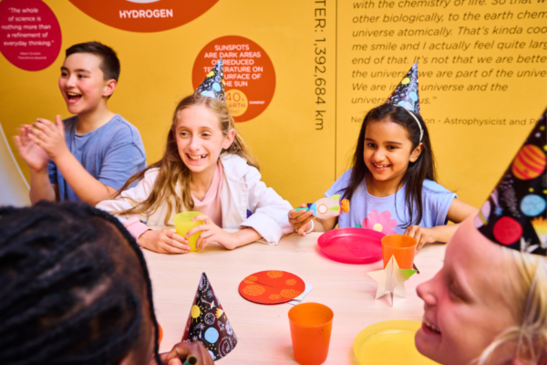 Three smiling children sitting at a table for a birthday party