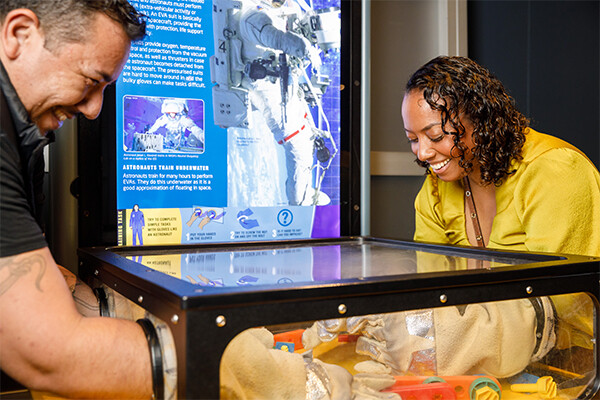 Two people having fun with an exhibit in the feature exhibition Astronaut