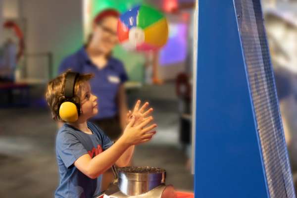 child wearing earmuffs interacting with Scitech exhibit